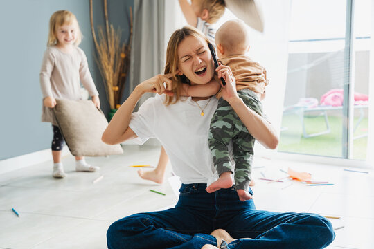 Woman alone with three children at home solving problems using phone.