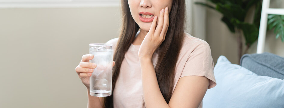 Face expression suffering from sensitive teeth, Asian young woman touching cheek