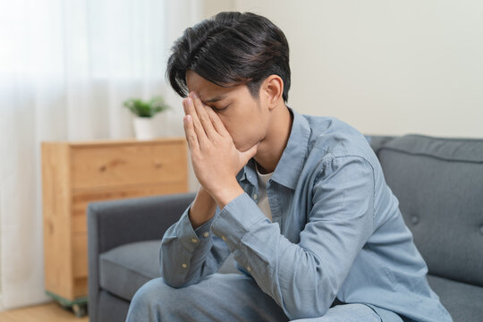 Stressed male feeling depressed and lonely on the sofa in the house.