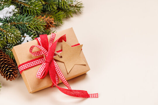 Gift box on snowy fir branches on beige background