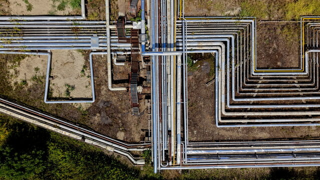 Aerial view of the petrochemical industry complex featuring a complex network of industrial pipes and metallic conduits running across the ground in Pancevo, Serbia.