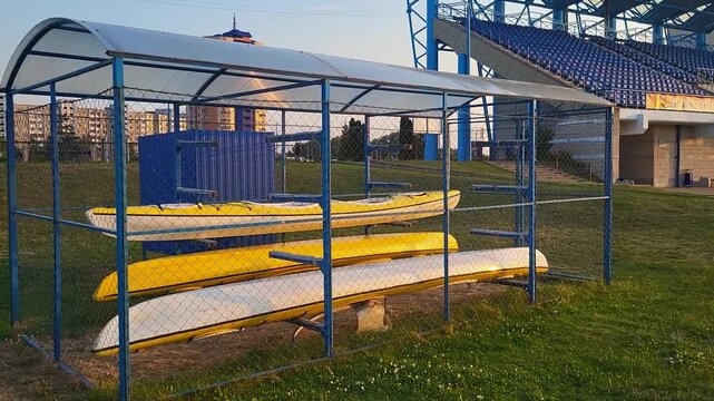Review of a professional rowing canal with kayaks and canoes storage at a stadium, athletic training facility, Olympic water sports preparation.