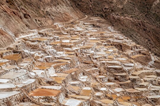 Terraced salt pools stepping down a steep dry valley