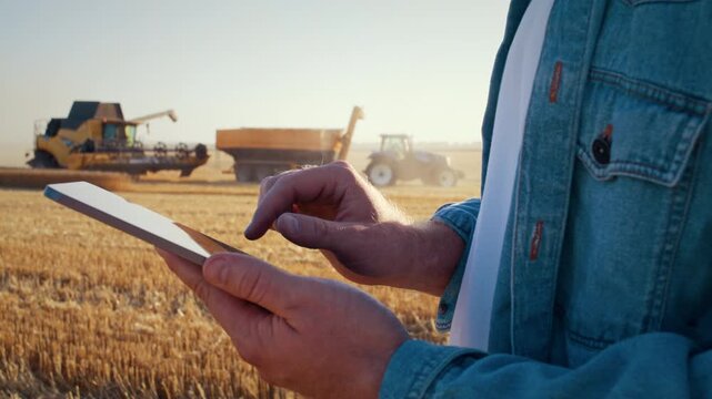 Farmer uses app on tablet and combine harvester cropping cereals