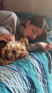 Tranquil young woman sleeping peacefully in bed with her adorable yorkshire terrier, sharing a serene moment of rest and deep emotional connection in the morning