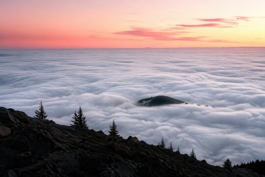 Sea of cloud filling a valley below a dark ridge at dawn