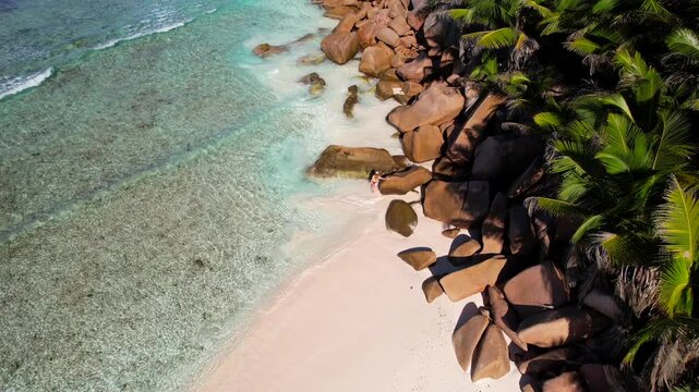 Woman explores a remote beach on La Digue in Seychelles. Aerial