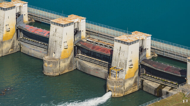 Aerial view of the hydroelectric dam on the Rhone River with massive concrete spillway gates and control towers regulating water flow in Le Pouzin, Auvergne-Rhone-Alpes, France.