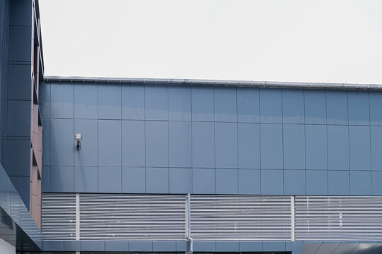 Modern Industrial Building Facade with Blue Metal Cladding Panels, CCTV Camera, and Exterior Wall Structure