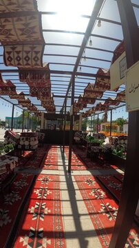 Traditional outdoor Arabic seating area shaded by patterned fabrics and red carpets.