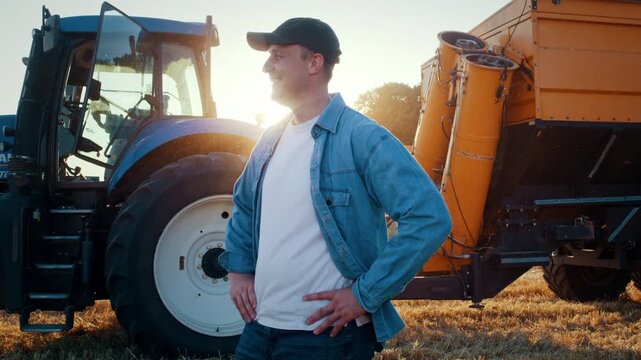 Smiling farmer with hands on hips stands near combine harvester