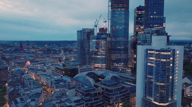 Aerial view of the modern Frankfurt am Main skyline featuring illuminated skyscrapers and urban architecture at twilight in Frankfurt am Main, Hessen, Germany.