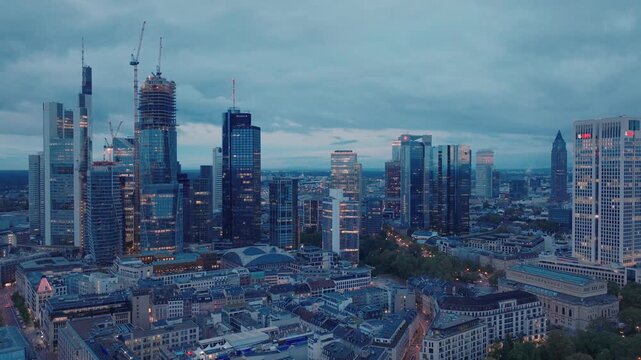 Aerial view of the Frankfurt am Main skyline featuring modern skyscrapers, glass office towers, and urban architecture under a cloudy evening sky in Frankfurt am Main, Hessen, Germany.