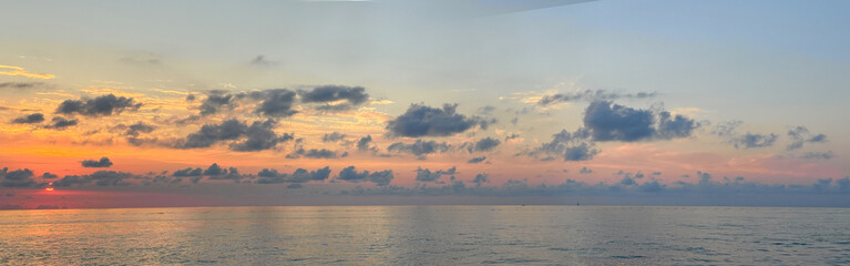 Fototapeta premium Sunset over the ocean with clouds in the sky and water during evening time