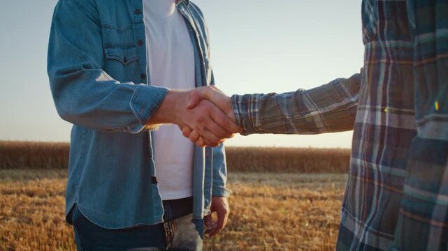 Male farmers handshake during field agreement at sunset