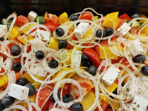 Fresh Mediterranean vegetable salad with feta cheese, black olives, tomatoes, cucumber, bell pepper and onion, close-up healthy food background.