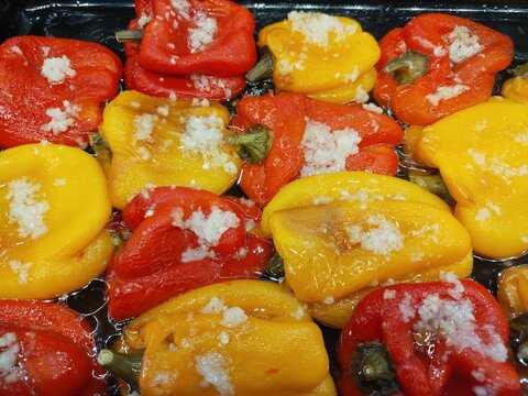 Colorful red and yellow bell peppers cooked with fresh garlic in oil, close-up of homemade vegetable appetizer or side dish.