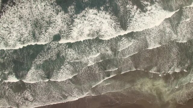 Aerial view of ocean waves crashing on the shore in Faroe Islands.