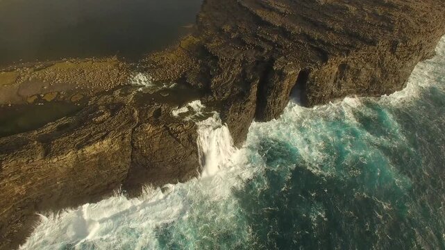 Aerial view of Mulafossur waterfall cascading from high cliffs into the Atlantic Ocean, Faroe Islands.