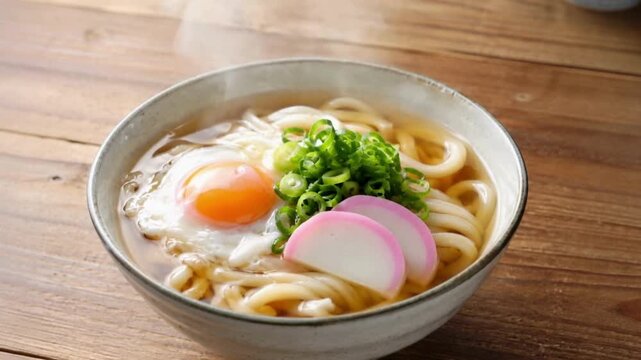 昼の家庭の食卓で温かいうどんの器から湯気が自然に立ち上がる風景