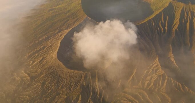 Aerial view of Mount Bromo and Tengger Caldera with volcanic smoke rising from the crater over the rugged landscape of East Java, Indonesia.
