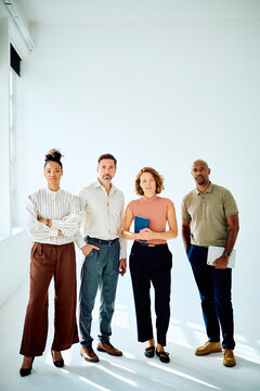 Professional multi-ethnic business team standing confidently on white background, collaborating and symbolizing unity and success
