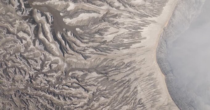 Aerial view of intricate volcanic erosion patterns and sandy textures of the Tengger Caldera near Mount Bromo, Indonesia.