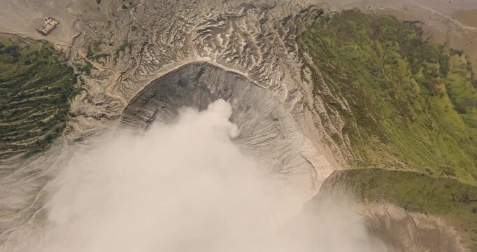 Aerial view of Mount Bromo and Tengger Caldera showing the volcanic crater with rising smoke and surrounding rugged landscape in Indonesia.