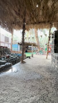 Traditional Arabic heritage site with a rustic stone water feature and thatched roof.