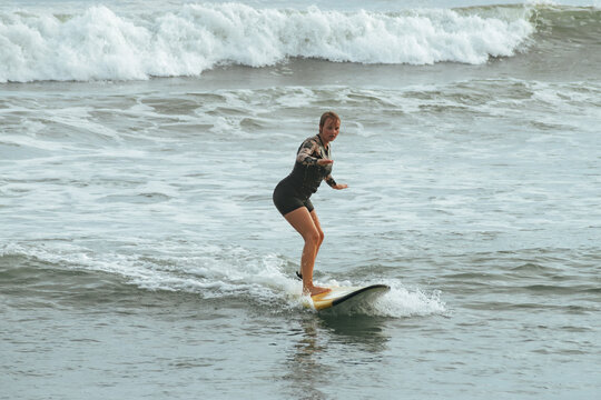 Young female surfer catching a wave on a yellow surfboard in the ocean