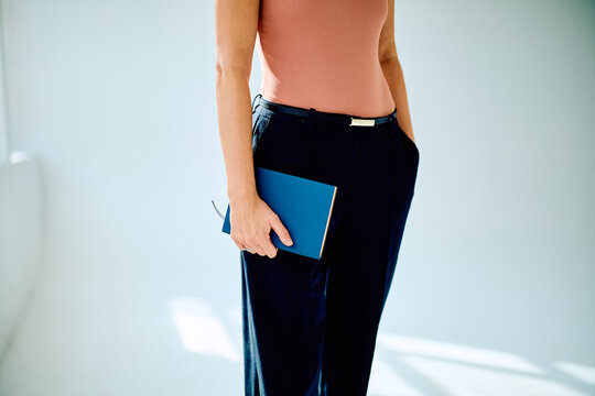 Woman holding a planner or book for organizing tasks, representing professional success, career development, and corporate planning