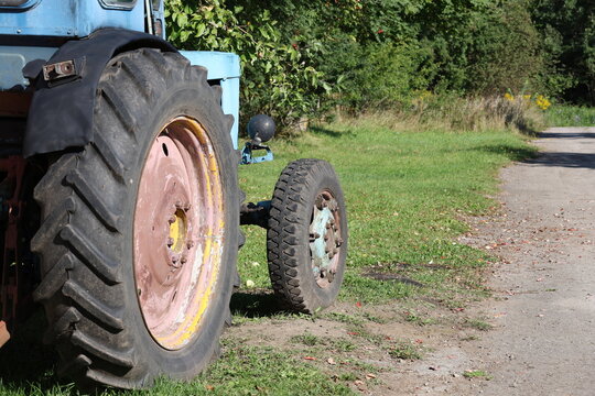 Blue tractor parked beside a country road in a rural landscape, agricultural machinery and countryside farming scene