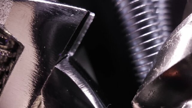 Extreme close-up of adjustable wrench mechanism tightening a bolt with visible threads and spring action.