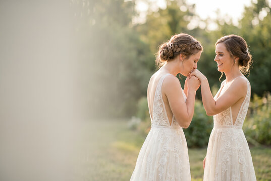 Two young women in white dresses laughing together outdoors