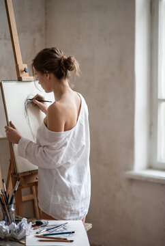 Young woman drawing on easel in bright minimalist studio space