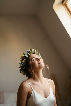 Young woman wearing floral crown looking upward in natural light