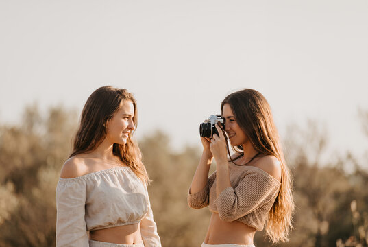 Young woman taking photo of friend outdoors in nature