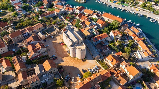 Peaceful waterfront of Vrboska features charming bridges, traditional stone houses and calm Adriatic Sea. Sunny summer day highlights authentic Mediterranean atmosphere of picturesque fishing village