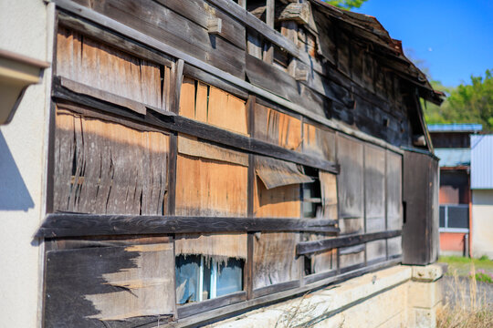 Severely Weathered Wooden Building with Peeling Exterior Siding and Damaged Window