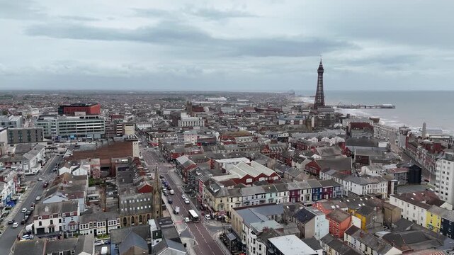 Aerial drone footage of Blackpool tower and seaside town coastline in UK with cityscape and ocean views.