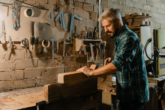 Carpenter in rustic workshop planing wood by hand on a workbench, woodworking craft and concentration