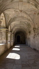 Fototapeta premium Stone cloister hallway with arches and game of light and shadows