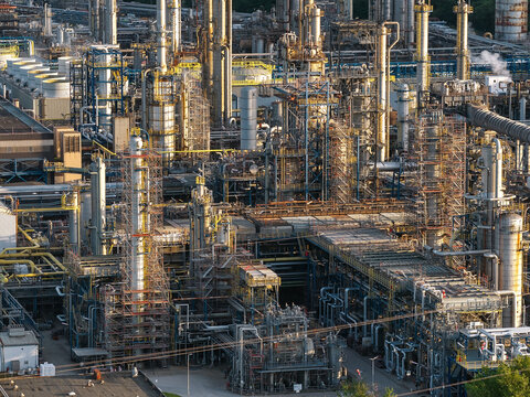 Aerial view of a large industrial chemical plant with complex piping systems, tall distillation columns, and scaffolding.