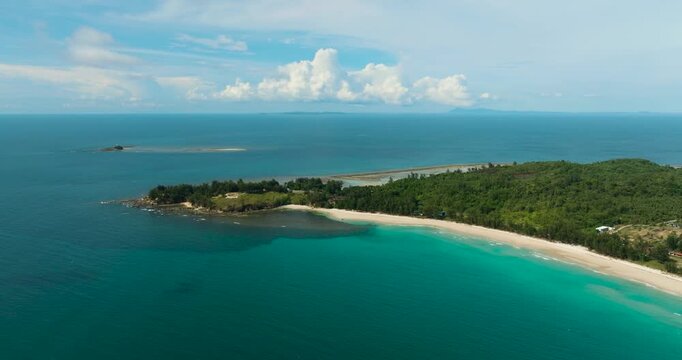 Aerial view of sandy beach with trees and sea surf with waves. The Tip of Borneo. Kalampunian Beach. Borneo, Malaysia.