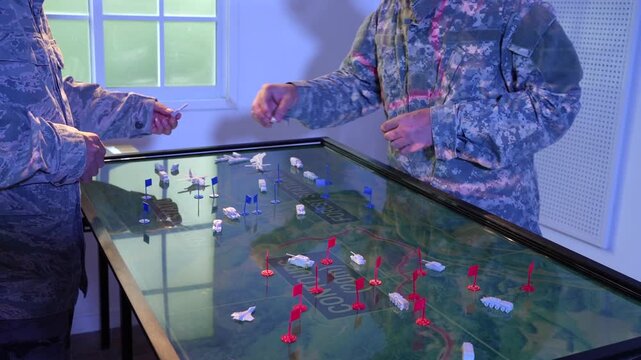 Military personnel in camouflage uniforms plan a tactical operation using a large digital map table with miniature markers in a blue-lit command room.