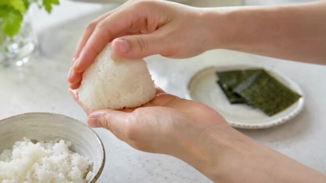 朝の家庭の台所で炊きたてのご飯を手でおにぎりに形づくる手元