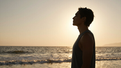Fototapeta premium Man Practicing Mindful Deep Breathing by the Ocean at Sunset, Copy space on the left