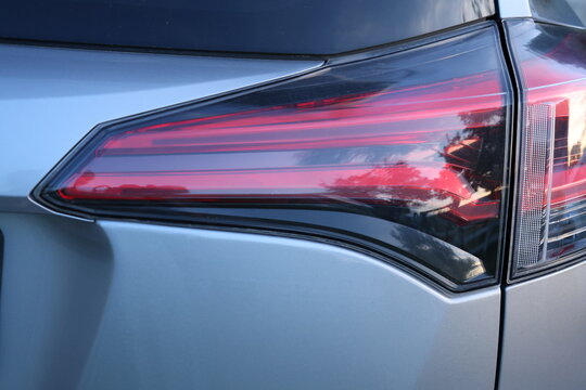 Close up of a modern car taillight with red rear light. Close-up detail of a modern automobile taillight with red rear lighting, showcasing automotive design, vehicle technology and exterior details.