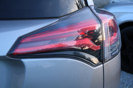 Close up of a modern car taillight with red rear light. Close-up detail of a modern automobile taillight with red rear lighting, showcasing automotive design, vehicle technology and exterior details.