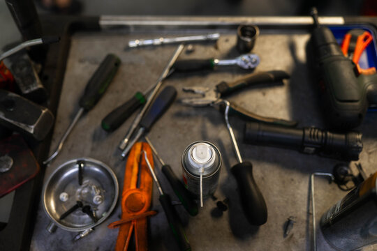 Penetrating spray among scattered tools on workbench upper view. Professional penetrant to work with rusty part on mechanic workplace